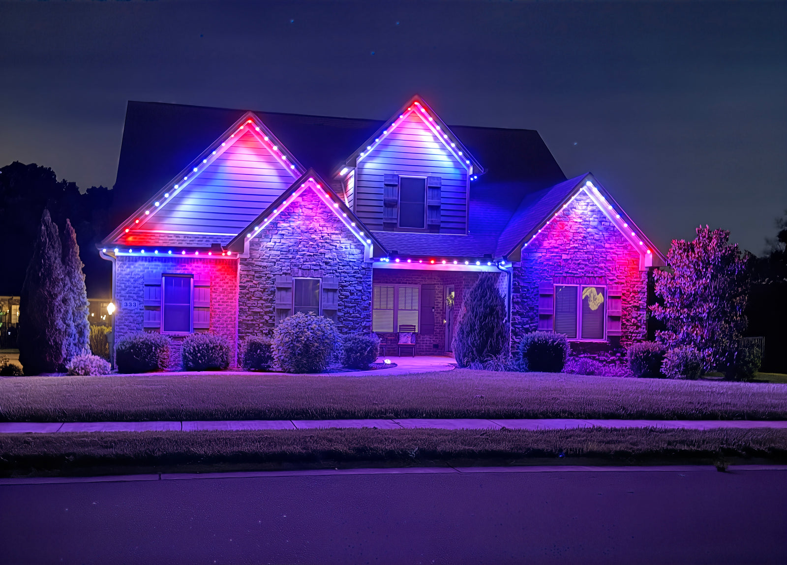 A home at night with red, white and blue RGBW roofline lighting on every gable